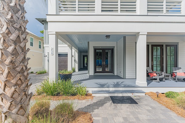 view of exterior entry featuring a porch, french doors, and a garage