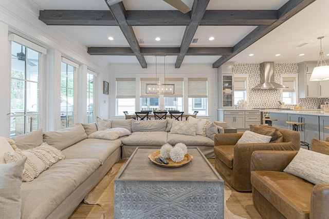 living room featuring beamed ceiling and a notable chandelier