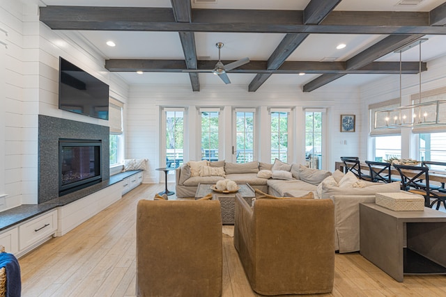 living room featuring light hardwood / wood-style floors, beam ceiling, and a wealth of natural light