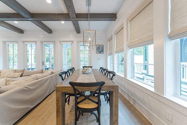 dining room featuring beamed ceiling, a notable chandelier, light hardwood / wood-style floors, and wood walls