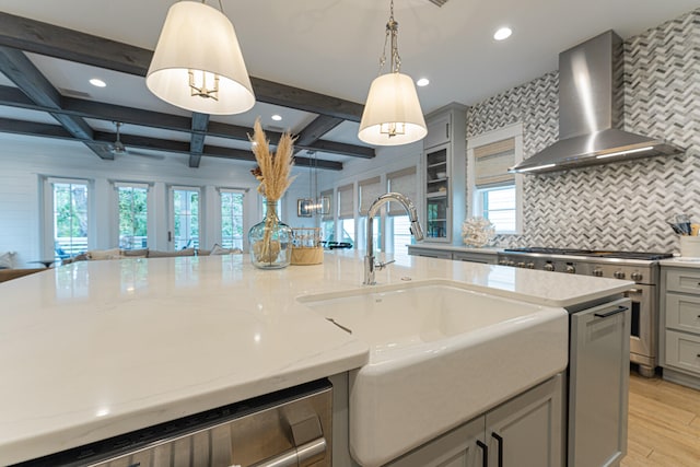 kitchen with gray cabinets, hanging light fixtures, beam ceiling, and wall chimney range hood