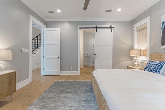 bedroom featuring ceiling fan, crown molding, light wood-type flooring, and a barn door