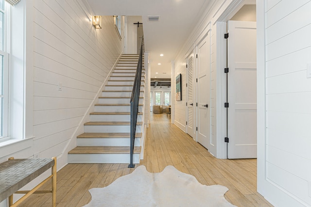 stairway featuring ornamental molding, hardwood / wood-style flooring, and wood walls