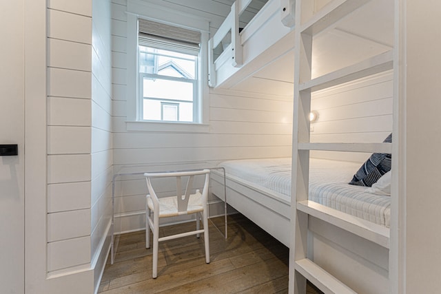 bedroom with hardwood / wood-style floors and wooden walls