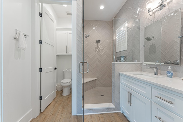 bathroom featuring toilet, an enclosed shower, vanity, and wood-type flooring