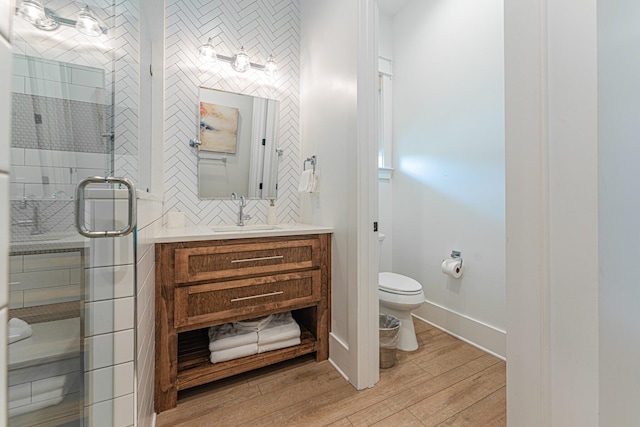 bathroom featuring vanity, toilet, a shower with door, and hardwood / wood-style floors