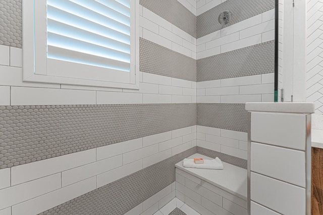 bathroom featuring tile walls and a tile shower