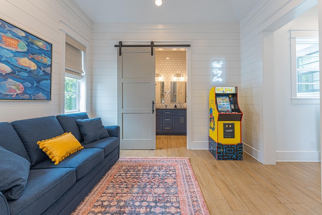 living room with light hardwood / wood-style floors, crown molding, and a barn door