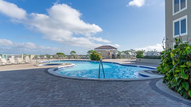 view of pool with a hot tub and a patio area