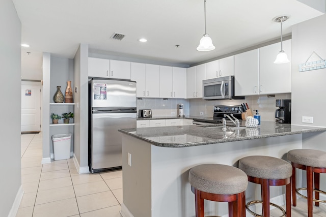 kitchen with pendant lighting, decorative backsplash, stainless steel appliances, and white cabinets