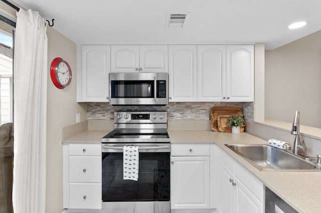 kitchen with white cabinets, decorative backsplash, sink, and appliances with stainless steel finishes