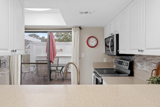 kitchen with white cabinets, backsplash, and stainless steel appliances