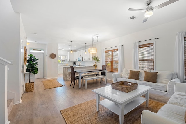 living room featuring ceiling fan and light hardwood / wood-style flooring