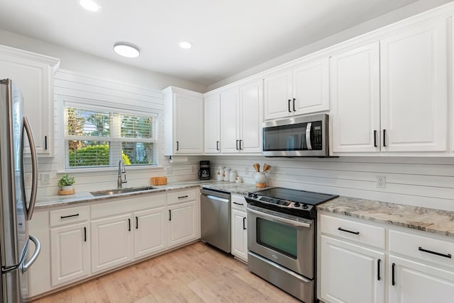 kitchen featuring stainless steel appliances, backsplash, sink, light hardwood / wood-style floors, and white cabinets