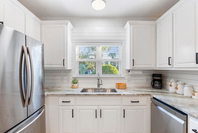 kitchen featuring appliances with stainless steel finishes, sink, light stone counters, and white cabinets