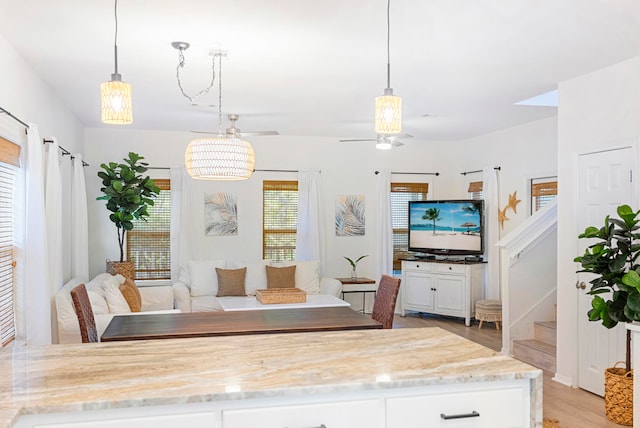 interior space with ceiling fan with notable chandelier and light wood-type flooring