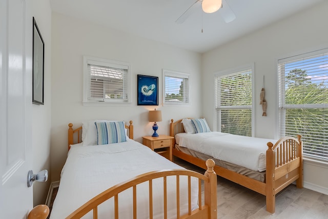 bedroom with ceiling fan, multiple windows, and light wood-type flooring