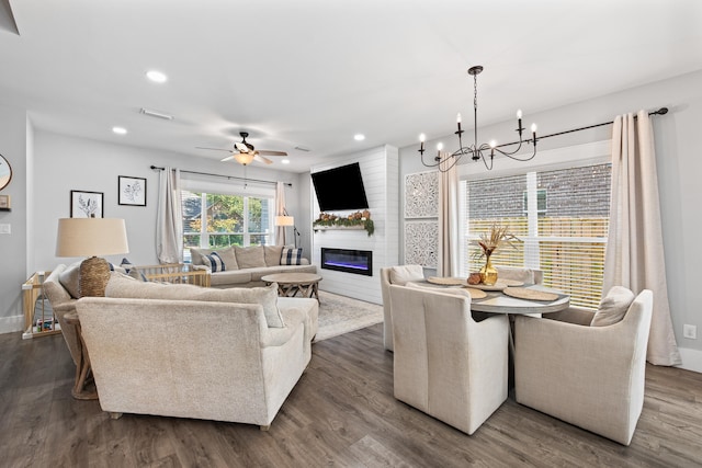 living room with ceiling fan with notable chandelier, a fireplace, and dark hardwood / wood-style floors