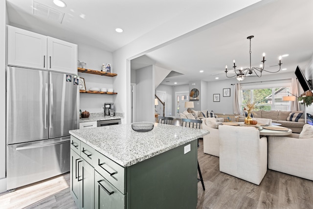 kitchen featuring white cabinetry, stainless steel refrigerator, a center island, and light wood-type flooring