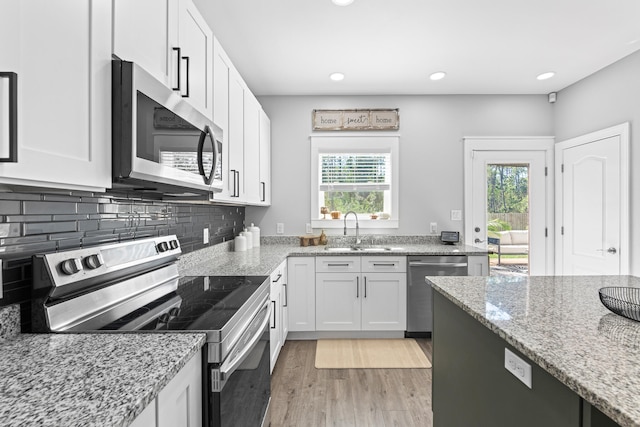 kitchen with appliances with stainless steel finishes, white cabinets, a healthy amount of sunlight, and sink