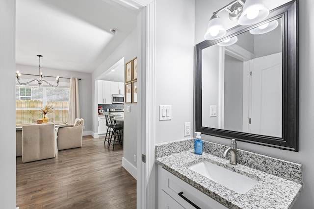 bathroom with vanity, a notable chandelier, tasteful backsplash, and hardwood / wood-style floors