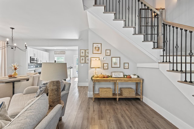 staircase with wood-type flooring and an inviting chandelier