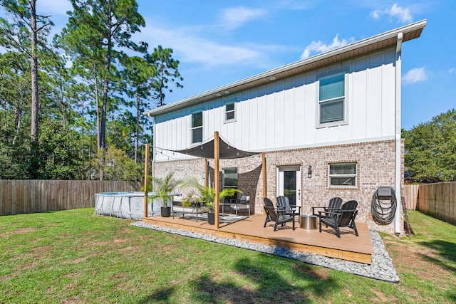 rear view of property with a yard and a pool side deck