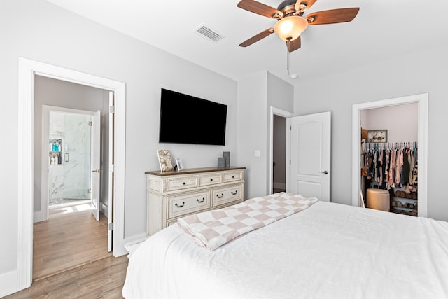 bedroom featuring ceiling fan, a spacious closet, light hardwood / wood-style floors, a closet, and ensuite bath