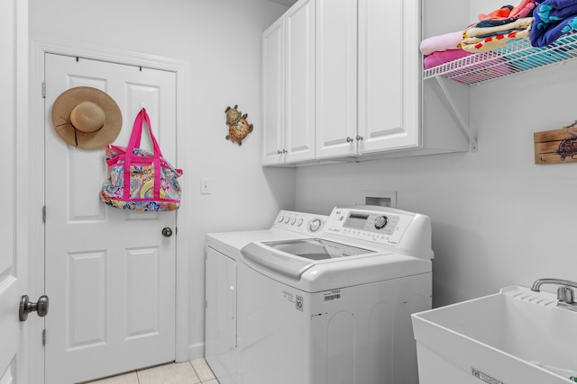 laundry room with cabinets, washer and dryer, light tile patterned floors, and sink