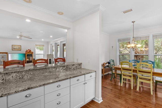 kitchen featuring light stone countertops, light hardwood / wood-style floors, hanging light fixtures, and white cabinetry