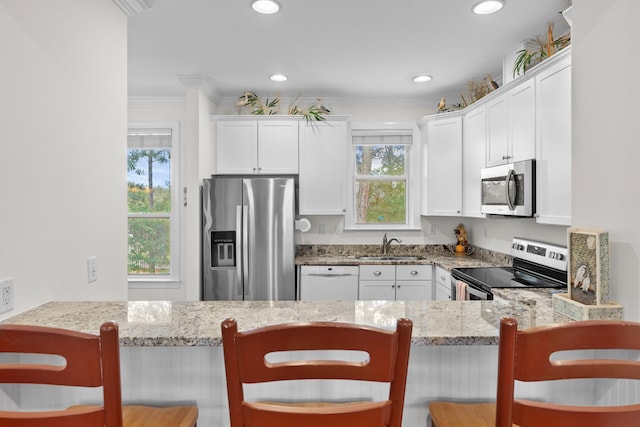 kitchen featuring appliances with stainless steel finishes, a kitchen bar, and a healthy amount of sunlight