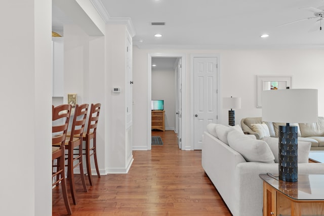 living room featuring light hardwood / wood-style floors, ceiling fan, and ornamental molding