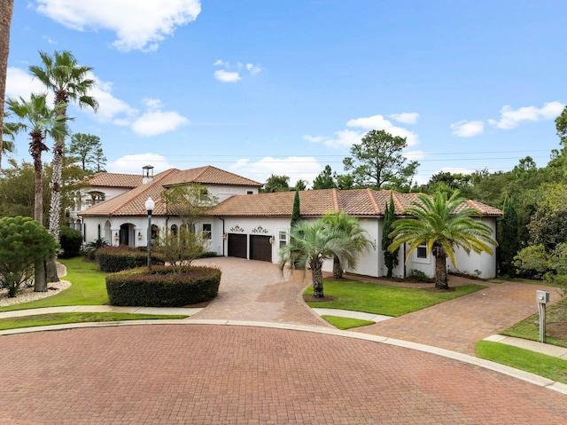 mediterranean / spanish-style home with a garage and a front lawn