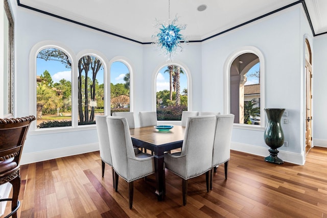 dining space with crown molding, hardwood / wood-style flooring, and a chandelier