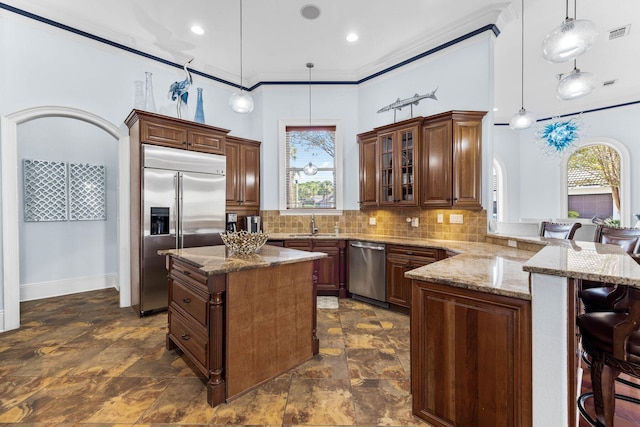 kitchen featuring a wealth of natural light, crown molding, appliances with stainless steel finishes, and hanging light fixtures