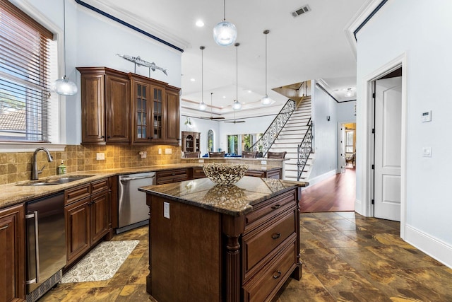 kitchen featuring dishwasher, dark stone countertops, sink, decorative light fixtures, and a center island