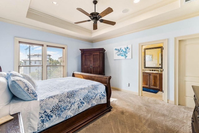 bedroom with a tray ceiling, ceiling fan, connected bathroom, crown molding, and light colored carpet