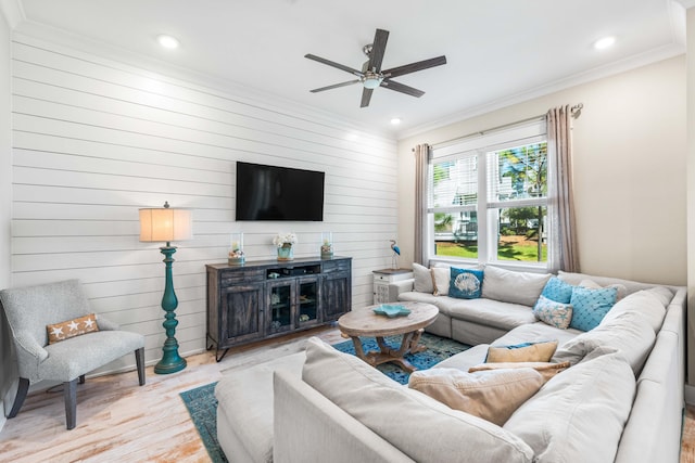 living room with crown molding, wood walls, light hardwood / wood-style flooring, and ceiling fan