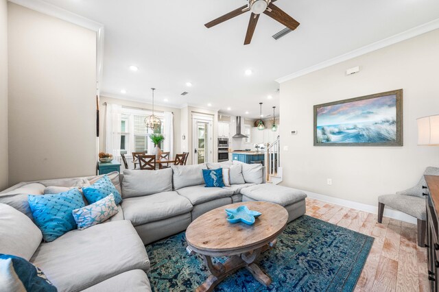 living room featuring ornamental molding, light hardwood / wood-style flooring, and ceiling fan with notable chandelier