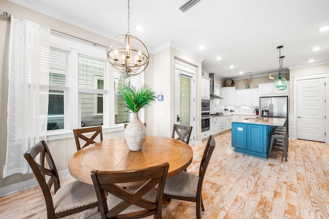 dining space with a notable chandelier, ornamental molding, sink, and light wood-type flooring