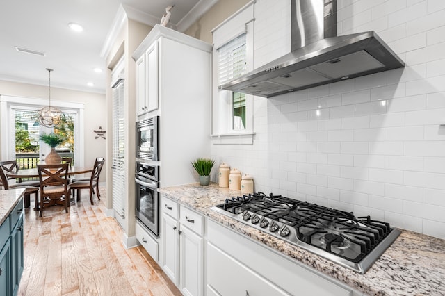 kitchen featuring wall chimney exhaust hood, stainless steel appliances, plenty of natural light, and light wood-type flooring