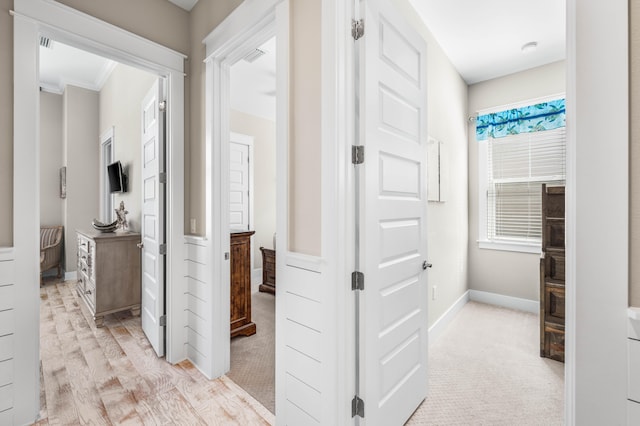 hallway featuring crown molding and light colored carpet