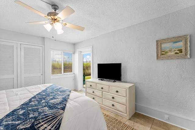 bedroom featuring a closet, ceiling fan, a textured ceiling, and light tile patterned floors