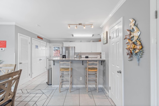 kitchen with a breakfast bar area, crown molding, stainless steel fridge with ice dispenser, and white cabinets