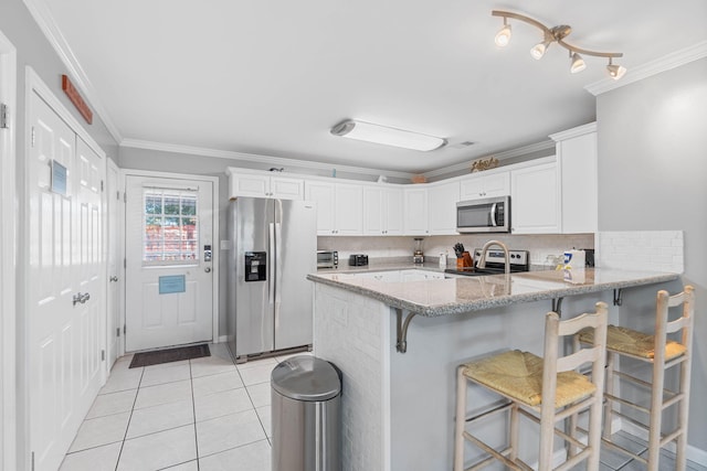 kitchen featuring white cabinetry, appliances with stainless steel finishes, a kitchen bar, and decorative backsplash