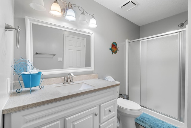 bathroom featuring vanity, a textured ceiling, toilet, and walk in shower