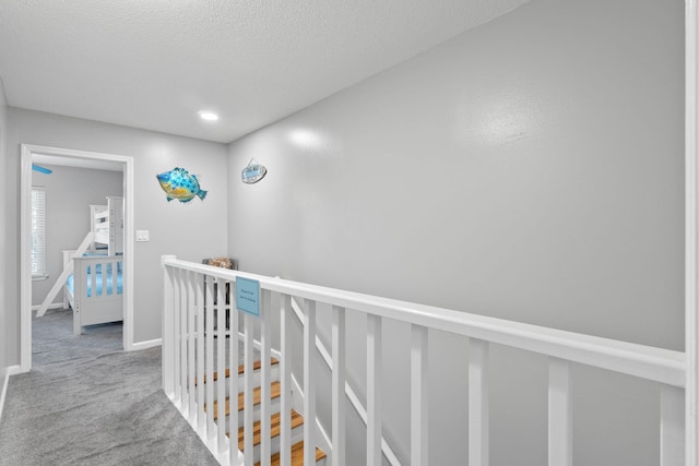 hall featuring carpet flooring and a textured ceiling