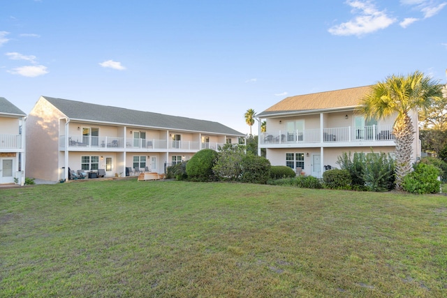 rear view of property with a yard and a balcony