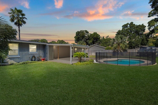 yard at dusk featuring a fenced in pool and a patio area