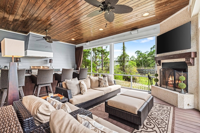 living room with wood walls, wood ceiling, hardwood / wood-style flooring, an outdoor fireplace, and ceiling fan